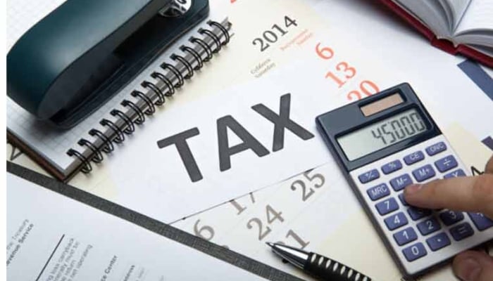 The representational  image depicts a calculator being used for tax-related calculations, likely for filing a tax return or assessing tax liability.