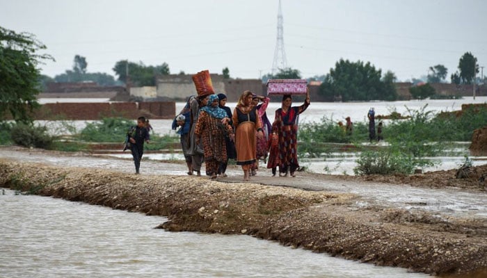 Women and children walk during the monsoon season in Jafferabad, Balochistan, August 25, 2022. — Reuters