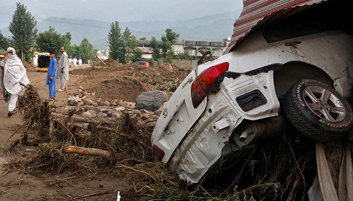 A woman walks past a damaged vehicle following heavy rain and floods in Buner district in Khyber Pakhtunkhwa on August 16, 2025. — Reuters