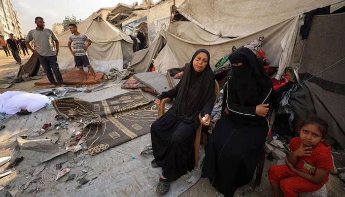 Palestinians women and a girl sit while others inspect the site of an overnight Israeli strike on a tent, in Gaza City, September 7, 2025. — Reuters
