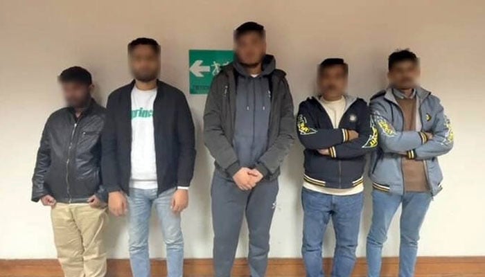 The handout photograph released on December 6, 2025 shows suspects deported from Sharjah for attempting to travel to the United Kingdom on forged British visas after their arrest in Lahore, Pakistan. —Federal Investigation Agency