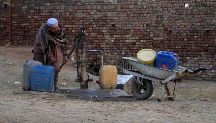 A man uses a hand-pump to collect drinking water for his family in a slum on the outskirts of Islamabad. — Reuters/File