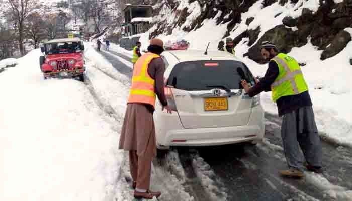 Workers rescuing a vehicle during heavy snowfall in KP. — PPI