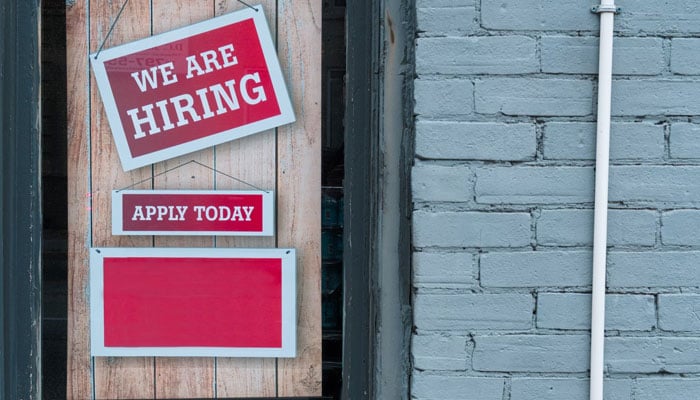 A representational image shows a sign board written Hiring and Apply Today. — Unsplash/File