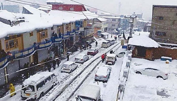 Heavy snowfall blankets the town, disrupting traffic and daily life as vehicles and pedestrians navigate through snow-covered streets. —TheNews/File