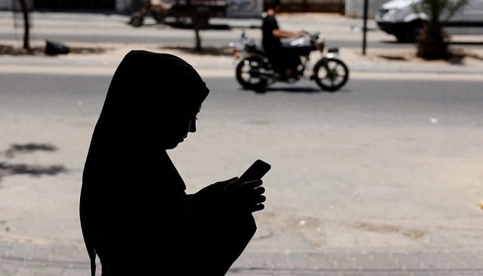 A Palestinian woman uses her smartphone as she stands outside the Gaza Womens Centre in Gaza City, May 31, 2022. Picture taken May 31, 2022. — Reuters
