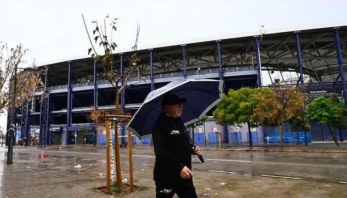 A man walks with an umbrella outside Ciutat de Valencia stadium after the Spanish league match between Levante UD and Villarreal CF was suspended due to a severe weather warning. —AFP/File