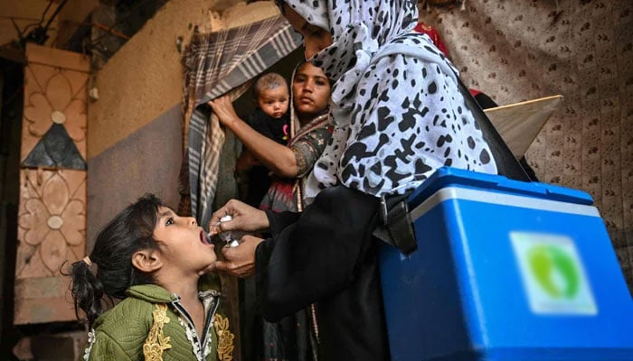 A health worker (R) administers polio drops to a child during a polio vaccination campaign in Karachi on February 3, 2025. — AFP