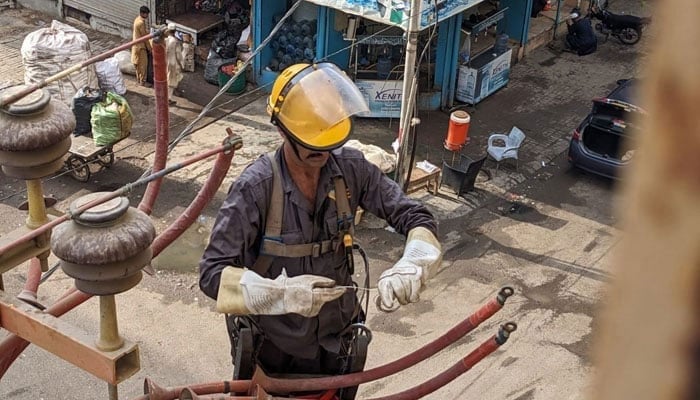 A KE worker seen working on a poll in this undated image.— Geo News/File