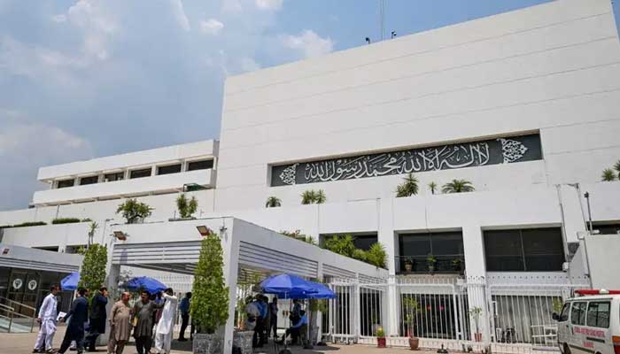 People stand outside the Parliament house during a budget session in Islamabad on June 26, 2024. — AFP