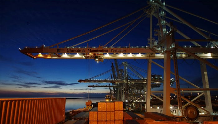 A cargo ship is docked at night with its lights on. —Unsplash/File