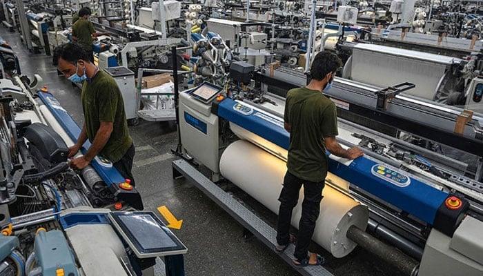 This picture shows workers operating machines at the Kohinoor Textile Mills in Lahore. — AFP/File