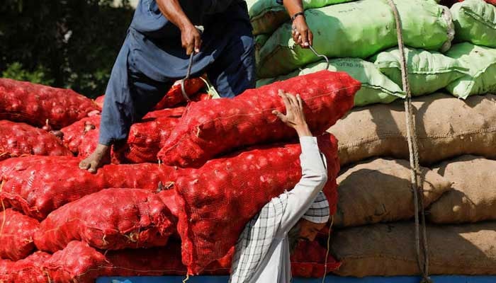 Labourers unload sacks of onion from a truck to supply at a market in Karachi. — Reuters/File