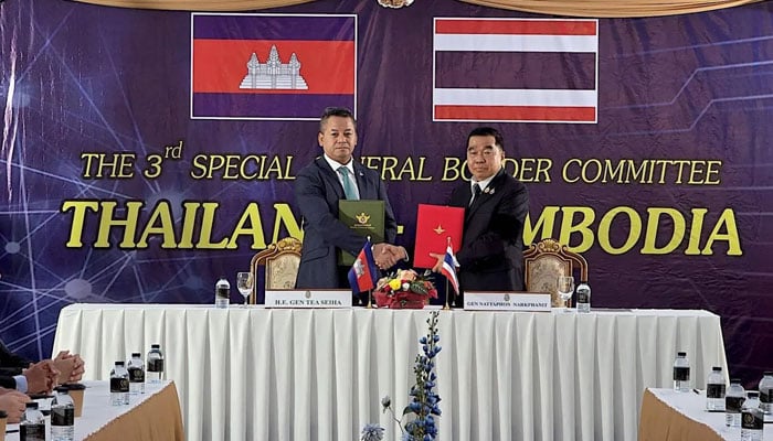 A handout photo shows Cambodian Defense Minister Tea Seiha (left) and Thai Defense Minister Natthaphon Narkphanit exchanging ceasefire agreement documents in Ban Pak Kard, Chanthaburi Province, Thailand, 27 December 2025.—Defense Ministry of Thailand