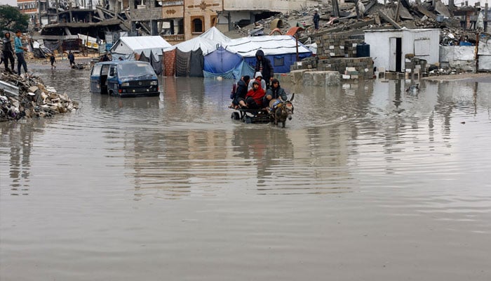 Displaced Palestinians ride a donkey-drawn cart on a rain-flooded street in Gaza City, December 12, 2025. —Reuters