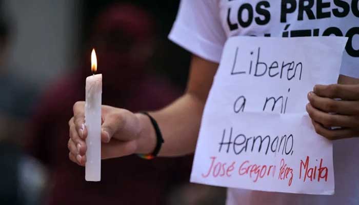 A man holds a candle and a sign asking for the release of his brother during a vigil called by the opposition demanding freedom for political prisoners arrested during a protest following the contested re-election of Maduro in Caracas. — AFP/File