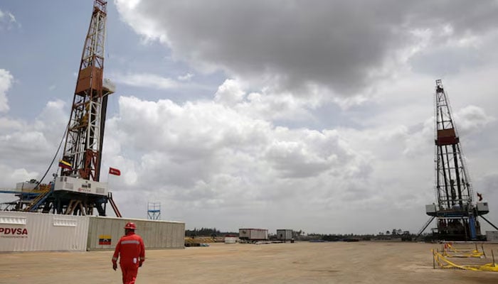 An oilfield worker walks next to drilling rigs at an oil well operated by Venezuelas state oil company PDVSA, in the oil rich Orinoco belt, near Morichal at the state of Monagas April 16, 2015.—Reuters