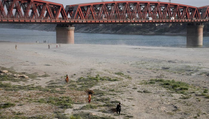 People walk on the dry riverbed of the Indus River in Hyderabad, Pakistan on April 24, 2025. — Reuters