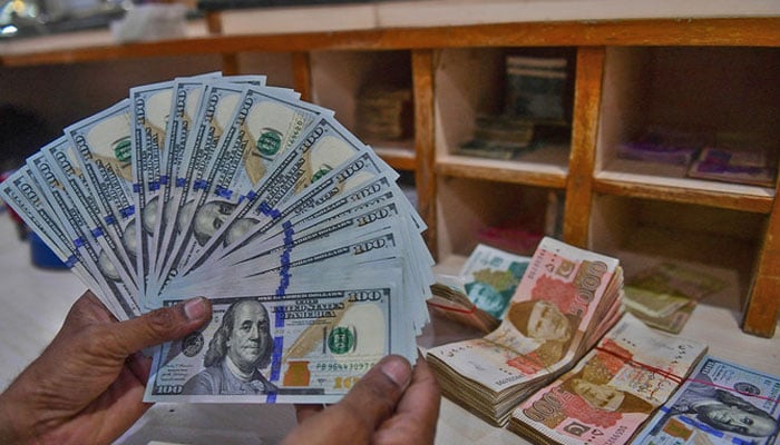 A foreign currency dealer counts US dollars at a shop in Karachi, Pakistan, on May 19, 2022. — AFP/File