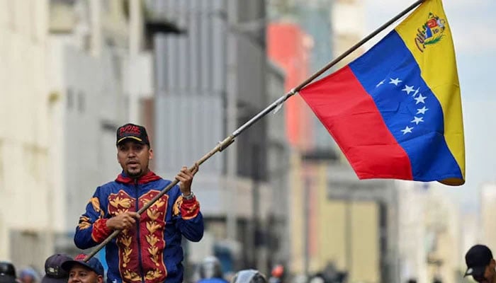 A demonstrator holds a Venezuelan flag during a march outside the National Assembly, in Caracas, Venezuela, January 5, 2026. — Reuters