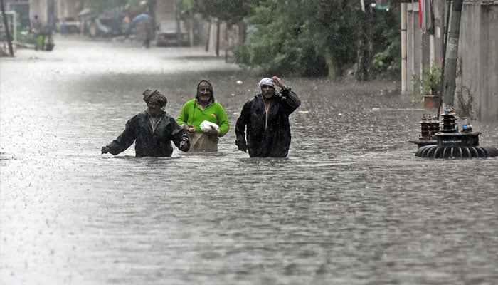 People wade through flooded Mukha Singh Estate Road during heavy monsoon rain in Rawalpindi. — Online/File
