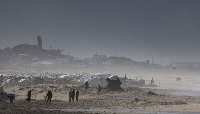 Palestinians gather near tents sheltering displaced people, amid a windstorm, in Gaza City, January 13, 2026.—Reuters