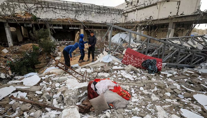 Palestinians inspect the damage at the site of a war-damaged building after parts of it collapsed, on a windy winter day, in Gaza City, January 13, 2026.—Reuters