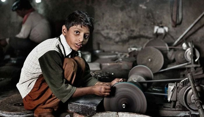 This image shows a young boy working on a grinding or polishing machine in a workshop. — APP/File