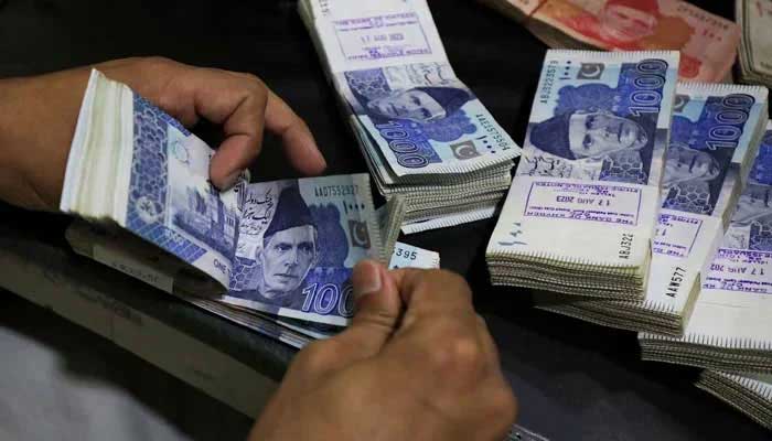 A bank employee counts Pakistani rupee notes at a bank in Peshawar, on August 22, 2023. — Reuters