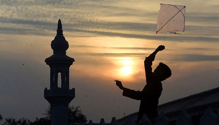 A Pakistani boy flies a kite on the roof of a mosque during sunset in Lahore, Pakistan. — AFP/File