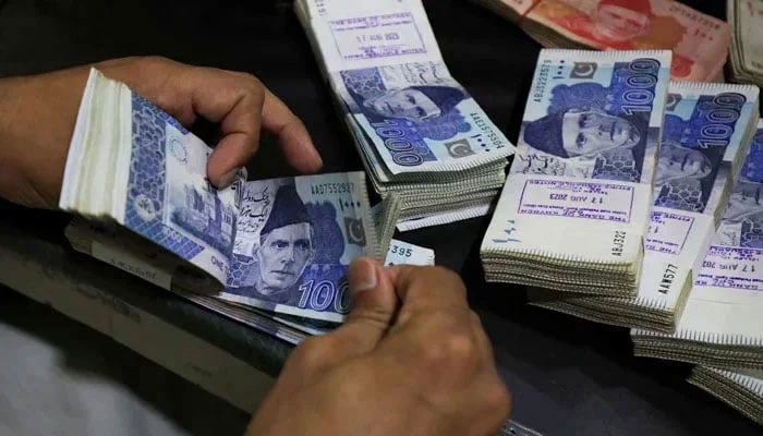 A bank employee counts Pakistani rupee notes at a bank in Peshawar, on August 22, 2023. — Reuters