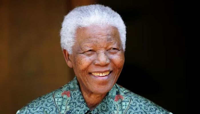 Former South African President Nelson Mandela smiles for photographers after a meeting with actor Tim Robbins at Mandelas home in Johannesburg September 22, 2005.—Reuters