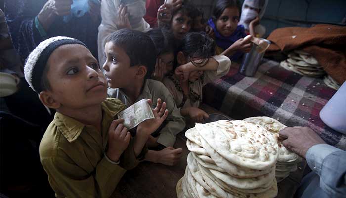 Children queue for subsidised bread at a food distribution centre in Karachi. — Reuters