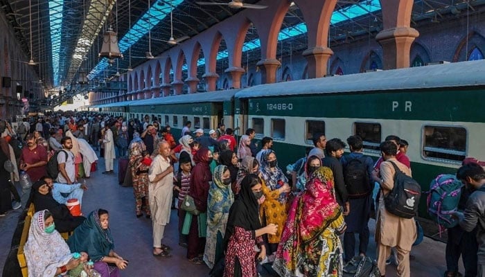 This representational image shows people waiting to board a train at a railway station in Lahore on June 15, 2024. — AFP