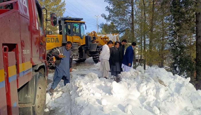 Heavy machinery and rescue officials remove snow to clear the road after the heavy snowfall in Abbottabad on January 25, 2026. — PPI