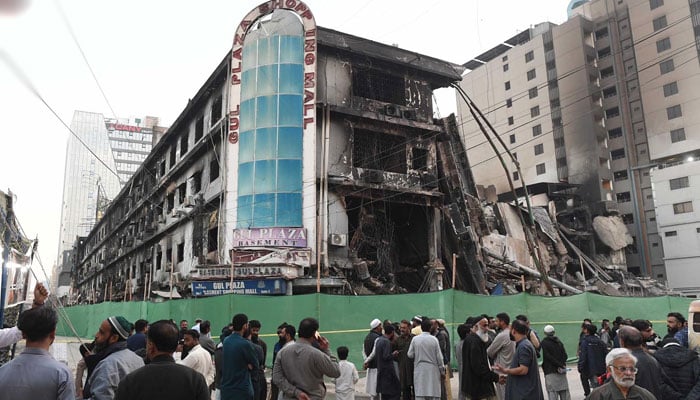 Traders and shop owners stand outside the burnt Gul Plaza on January 30, 2026. — INP