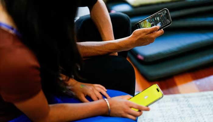 Two school students pose with their mobile showing social media applications in Melbourne, Australia, November 28, 2024. — Reuters