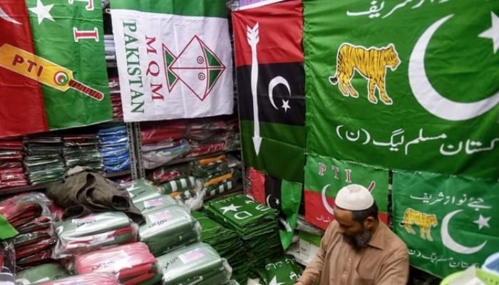 A shopkeeper arranges flags of political parties at his shop ahead of the upcoming general elections in Karachi. — AFP/File
