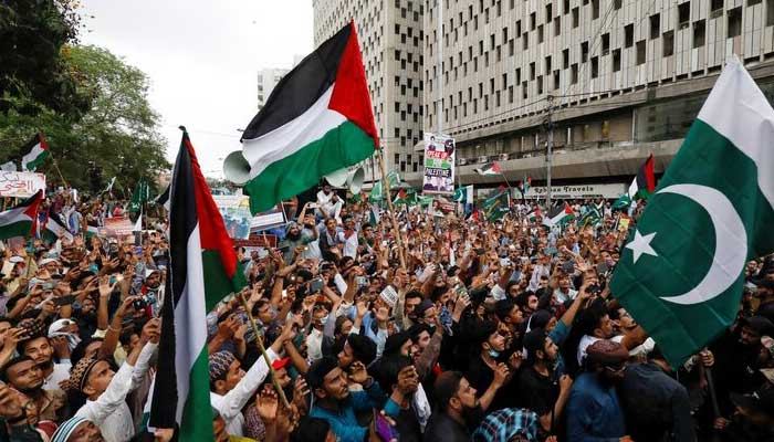 People carry flags as they chant slogans to express solidarity with Palestinian people and to protest against Israel, during a rally in Karachi. — Reuters/File