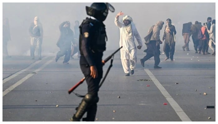 A PTI supporter gestures as police fire tear gas shells to disperse the crowd in Islamabad on Nov 26. — AFP