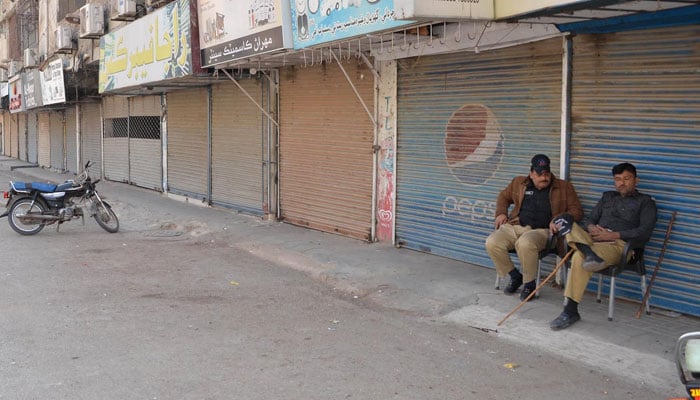 Police personnel sit in front of closed shops during the protest called by the opposition parties against alleged Feb 8 poll rigging on February 8, 2026. — INP