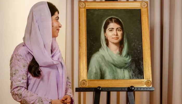 Pakistans Nobel Peace Prize laureate Malala Yousafzai is seen standing by her portrait unveiled at Oxford University’s Lady Margaret Hall. — Reporter