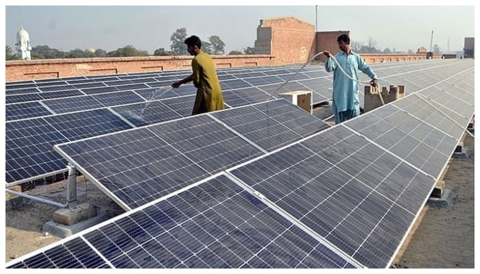 Workers washing 300 KWP solar PV system after its installation at Nishtar Medical University and Hospital in Multan, on December 4, 2022. — APP