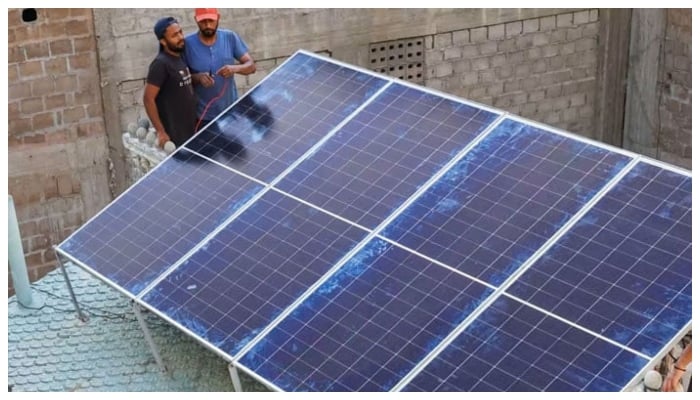 Technicians work on solar panels installed on the roof of a house in Karachi. — Reuters/File