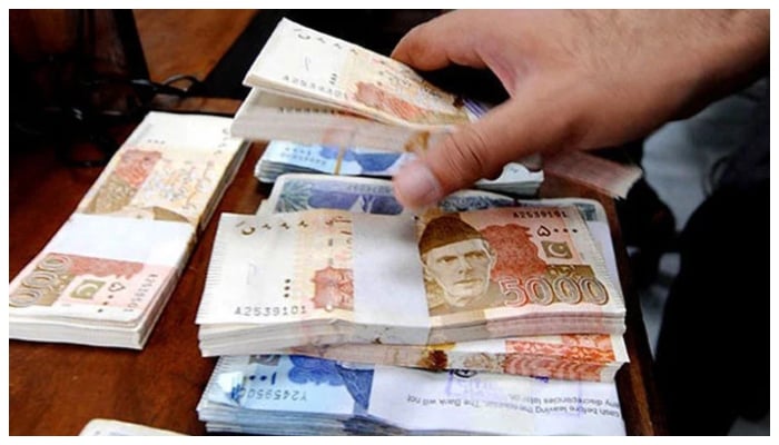 A person arranges stacks of Pakistani banknotes. — AFP/File