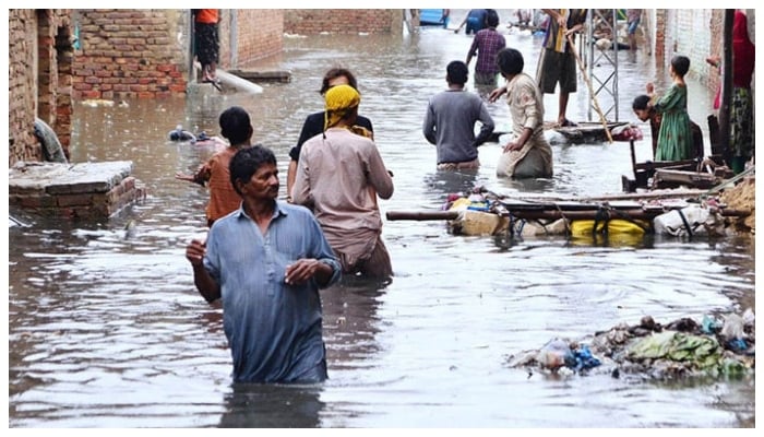 Residents wade through floodwaters following heavy rains in Hyderabad, August 2022.— APP