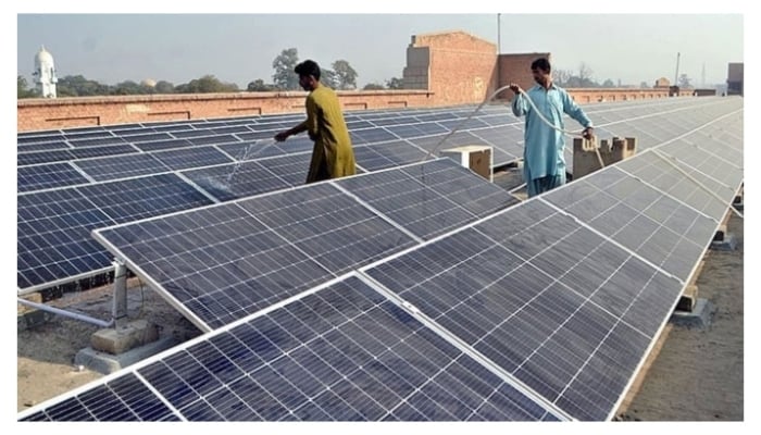 Workers washing 300 KWP solar PV system after its installation at Nishtar Medical University and Hospital in Multan, on December 4, 2022. — APP