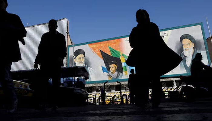 People walk near a mural featuring images of Irans Supreme Leader Ayatollah Ali Khamenei and leader of Irans 1979 Islamic Revolution Ayatollah Ruhollah Khomeini, on a street in Tehran, Iran, February 17, 2026. — Reuters