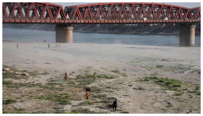 People walk on the dry riverbed of the Indus River in Hyderabad, Pakistan on April 24, 2025. — Reuters