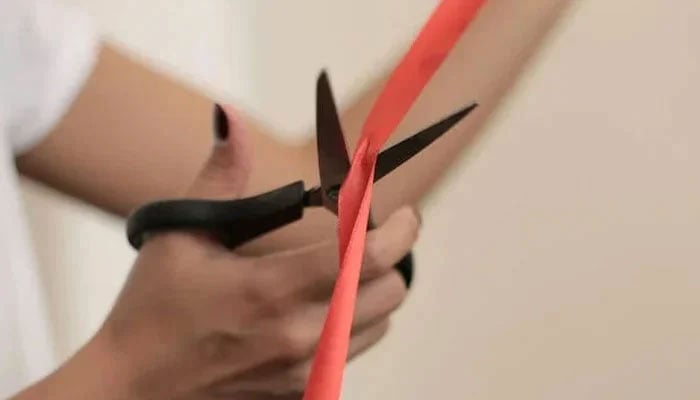 A representational image of a person cutting an inauguration ribbon. — Pexels/File